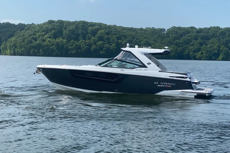 Slide: The Image of 2023 Monterey 378SS Super Sport boat cruising on a lake with forested shoreline. - 5