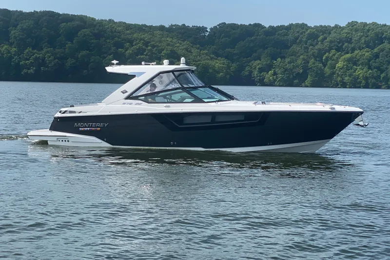 The Image of 2023 Monterey 378SS Super Sport boat cruising on a serene lake with lush green forest backdrop. - 1