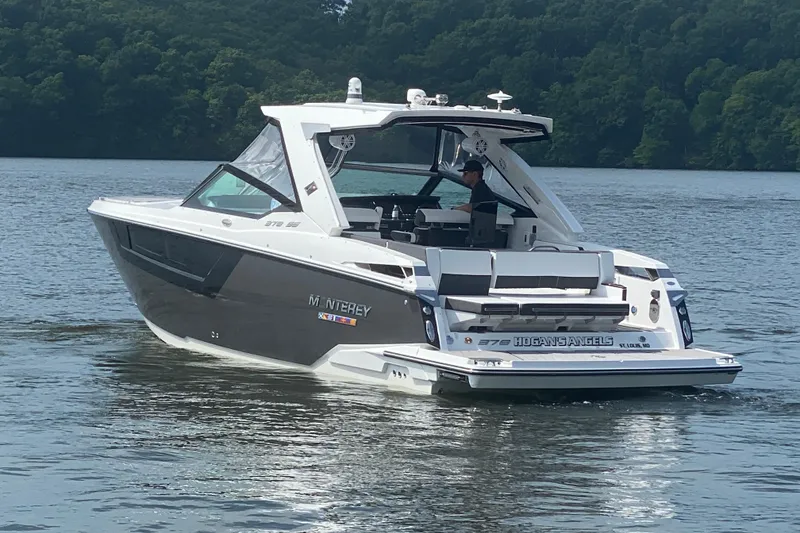 Slide: The Image of 2023 Monterey 378SS Super Sport boat cruising on a lake with lush green forest backdrop. - 8