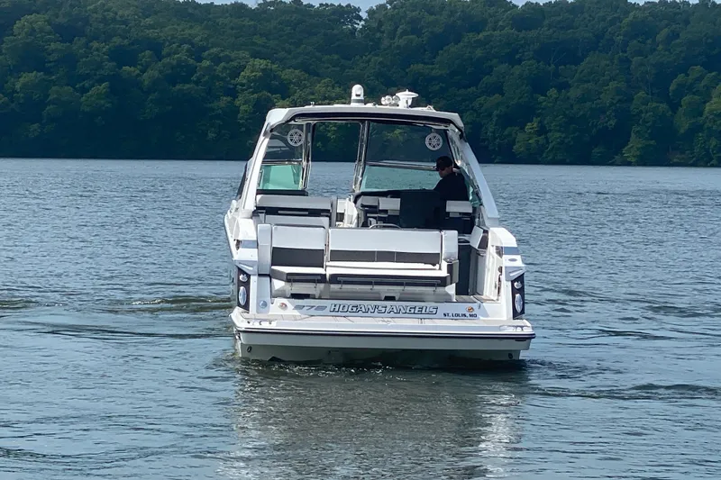 Slide: The Image of 2023 Monterey 378SS Super Sport boat cruising on a lake with lush green forest backdrop. - 9