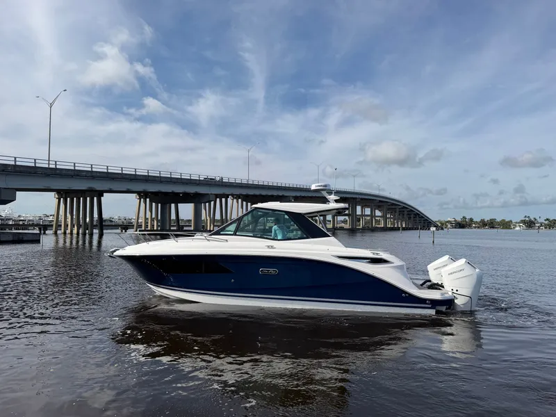 Slide: The Image of A 2027 Sea Ray Sundancer 320 Outboard cruising on calm waters beneath a bridge. - 15