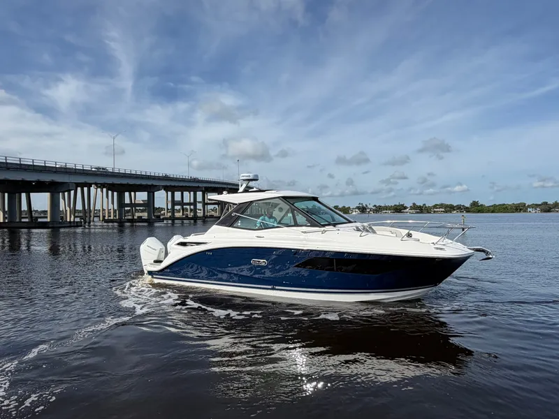 Slide: The Image of A sleek, modern boat with a blue hull cruises on calm water under a bridge. - 2