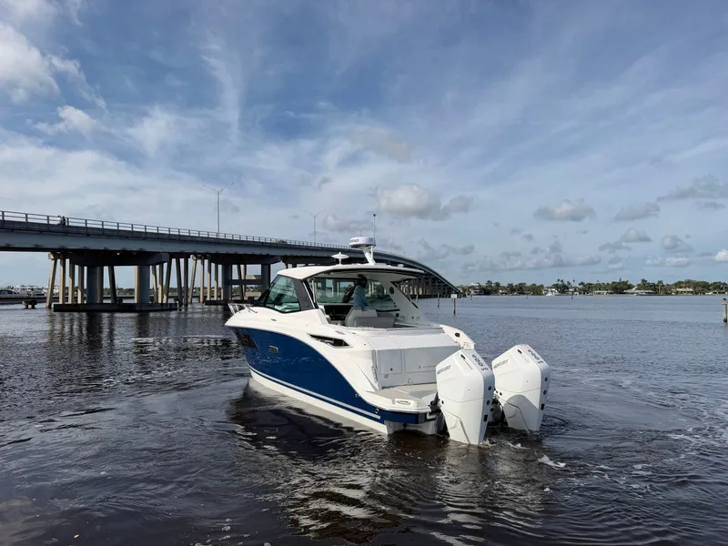 Slide: The Image of A 2027 Sea Ray Sundancer 320 Outboard cruising on calm waters under a bridge. - 8
