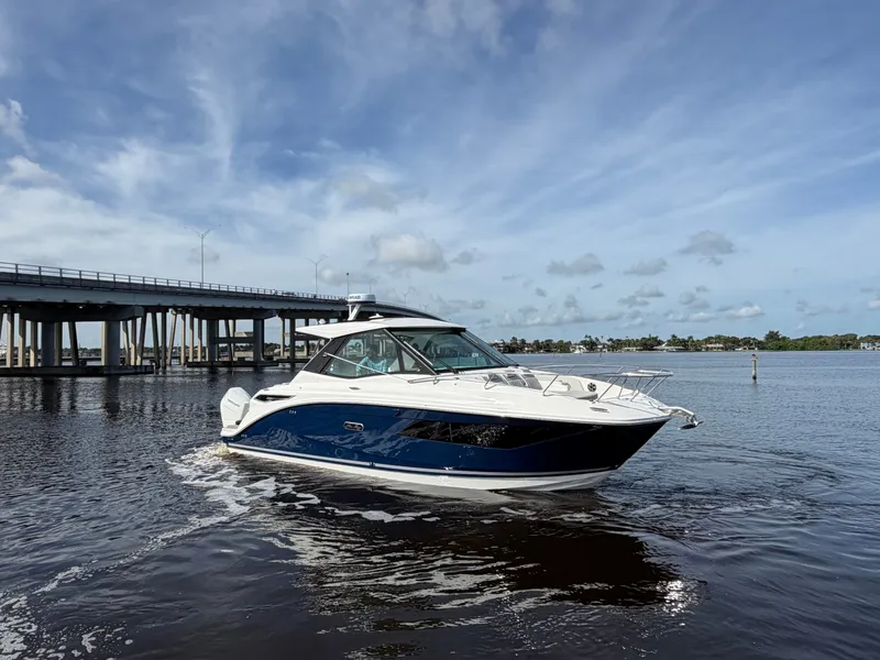 Slide: The Image of A 2027 Sea Ray Sundancer 320 Outboard cruising on calm waters beneath a bridge. - 3