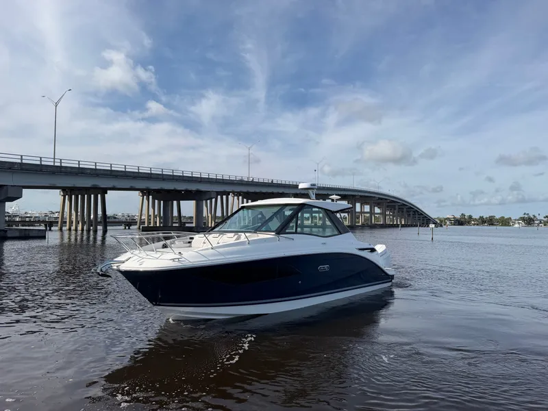 Slide: The Image of A 2027 Sea Ray Sundancer 320 Outboard cruising on calm waters beneath a bridge. - 12
