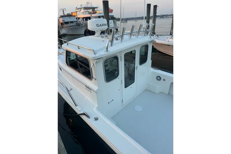 Slide: The Image of 2023 Parker 2320 SL Sport Cabin boat docked, featuring a sleek white cabin and Garmin equipment. - 10