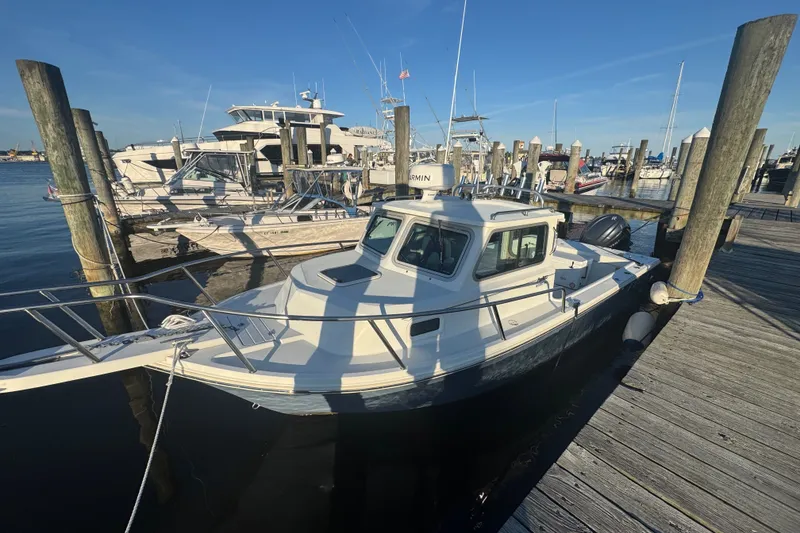The Image of 2023 Parker 2320 SL Sport Cabin boat docked at a marina under clear blue skies. - 4