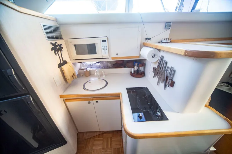 Slide: The Image of Compact kitchen in a 1996 CRUISERS YACHTS 3580 Flybridge, featuring stove, microwave, and knife set. - 45