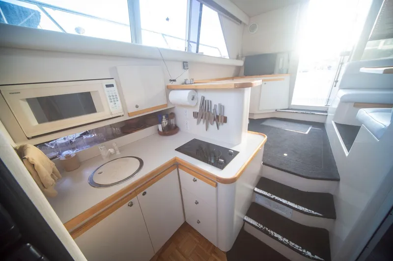 Slide: The Image of Interior of 1996 CRUISERS YACHTS 3580 Flybridge, featuring a compact kitchen with microwave and stove. - 46