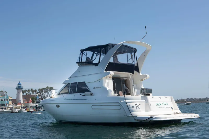 Slide: The Image of 1996 CRUISERS YACHTS 3580 Flybridge on water near a lighthouse and marina. - 2