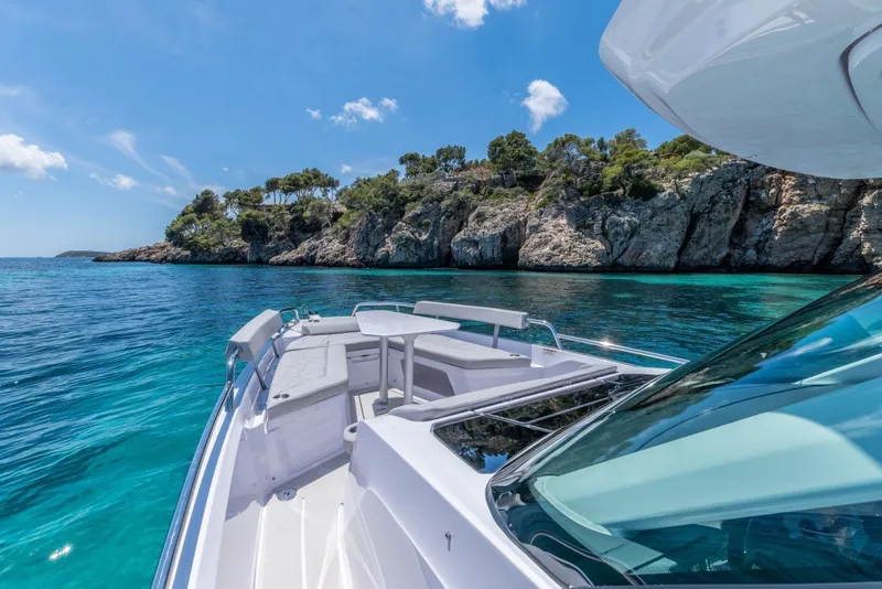 Slide: The Image of 2027 Axopar 29 Sun-Top boat cruising near rocky coastline under clear blue sky. - 9