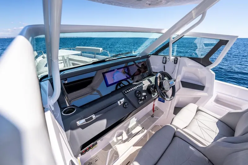 Slide: The Image of 2027 Axopar 29 Sun-Top boat interior with modern dashboard and steering wheel on open water. - 15