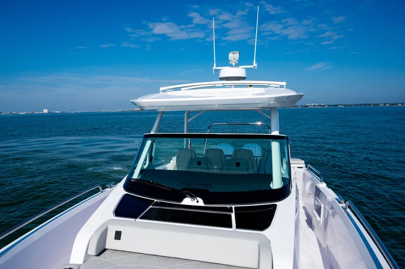 Slide: The Image of 2027 Axopar 29 Sun-Top boat cruising on open water under clear blue skies. - 8