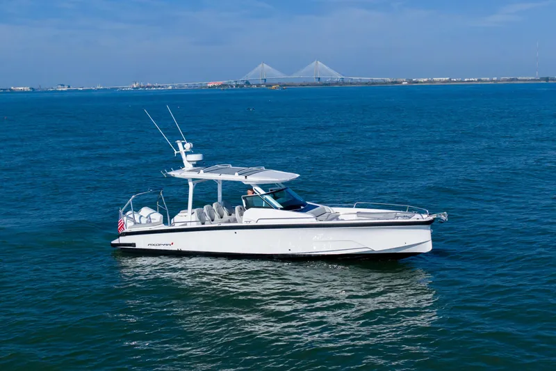 Slide: The Image of 2027 Axopar 29 Sun-Top boat cruising on open water with a bridge in the background. - 1