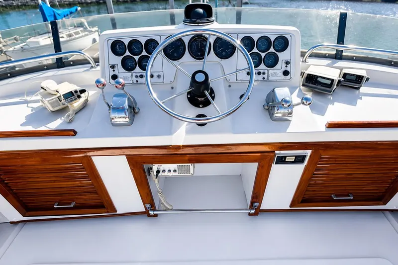 Slide: The Image of 1983 Silverton 402 Motor Yacht helm with steering wheel, gauges, and wooden accents. - 8
