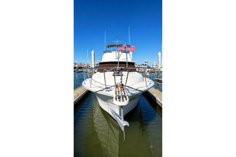 Slide: The Image of 1983 Silverton 402 Motor Yacht docked in marina, clear blue sky, American flags displayed. - 3