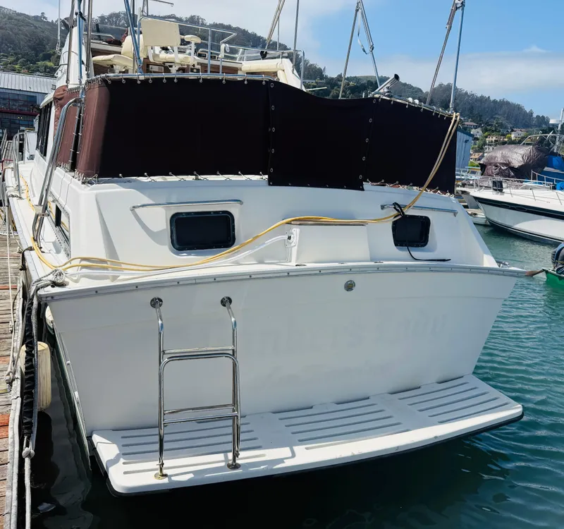 Slide: The Image of 1983 Silverton 402 Motor Yacht docked at marina, rear view with ladder and deck. - 7