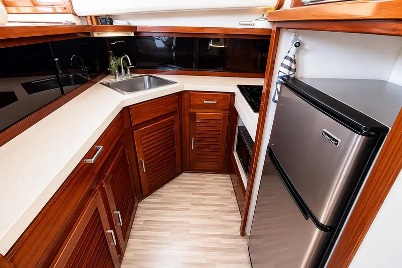 Slide: The Image of 1983 Silverton 402 Motor Yacht kitchen with wood cabinets, stainless steel sink, and compact fridge. - 18