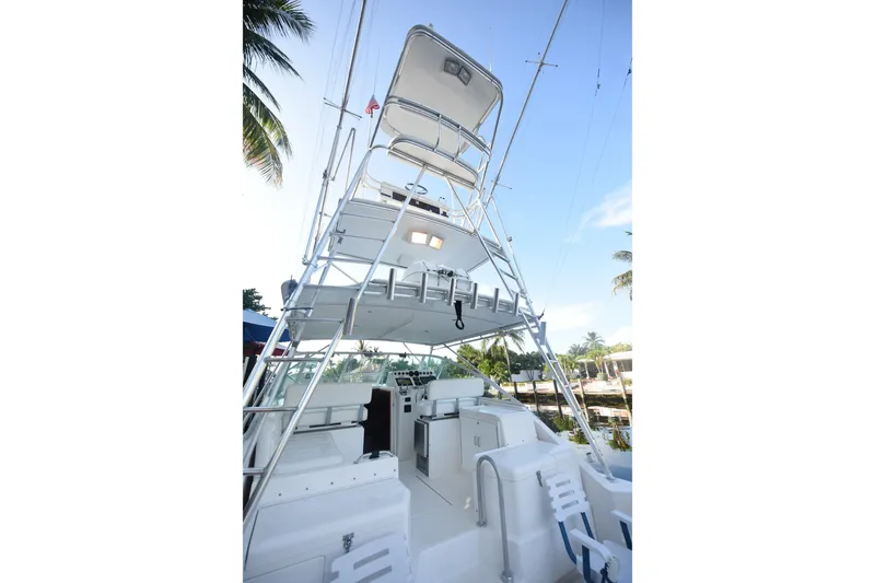 Slide: The Image of 2002 Cabo 35 Express boat with tower, docked near palm trees under clear blue sky. - 11