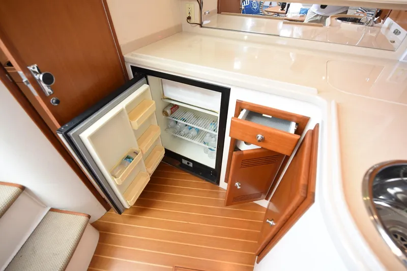 Slide: The Image of Interior of 2002 Cabo 35 Express yacht with open fridge and wooden cabinetry. - 93
