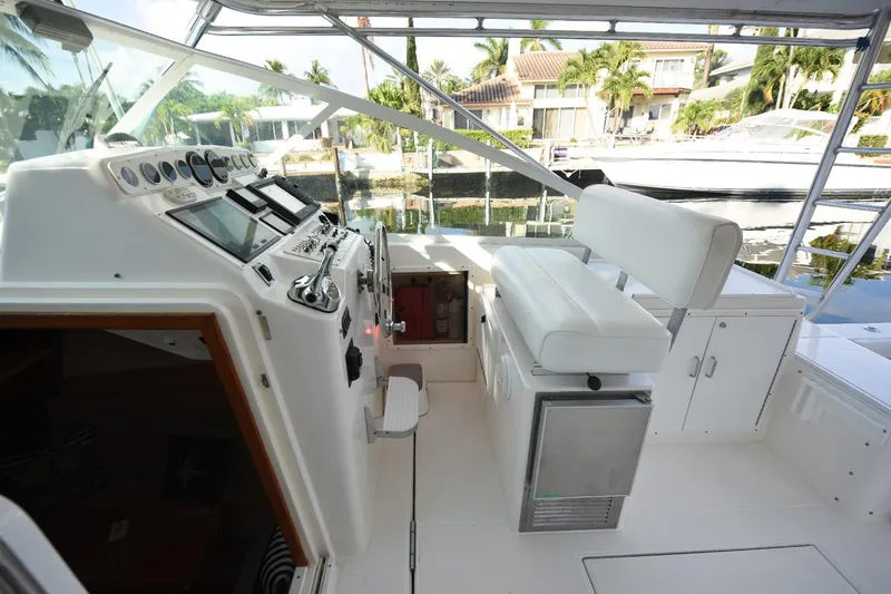 Slide: The Image of 2002 Cabo 35 Express boat cockpit with helm, white seating, and control panel. - 63