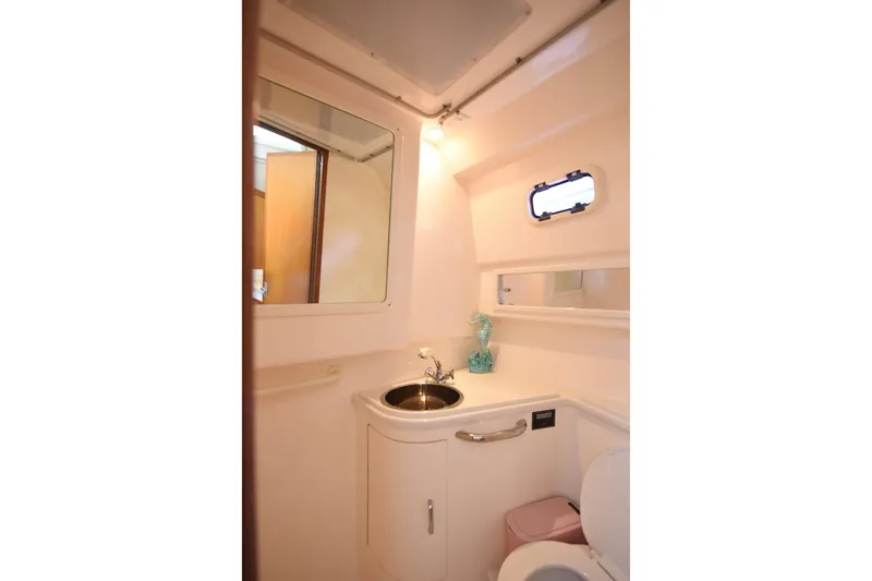 Slide: The Image of Compact bathroom in 2002 Cabo 35 Express boat with sink, mirror, and porthole window. - 91