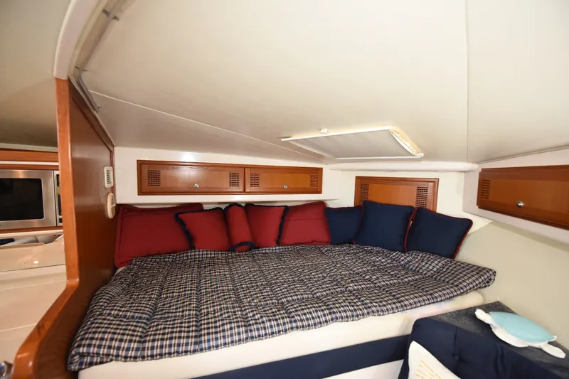 Slide: The Image of Cozy cabin interior of 2002 Cabo 35 Express with plaid bedding and colorful cushions. - 78