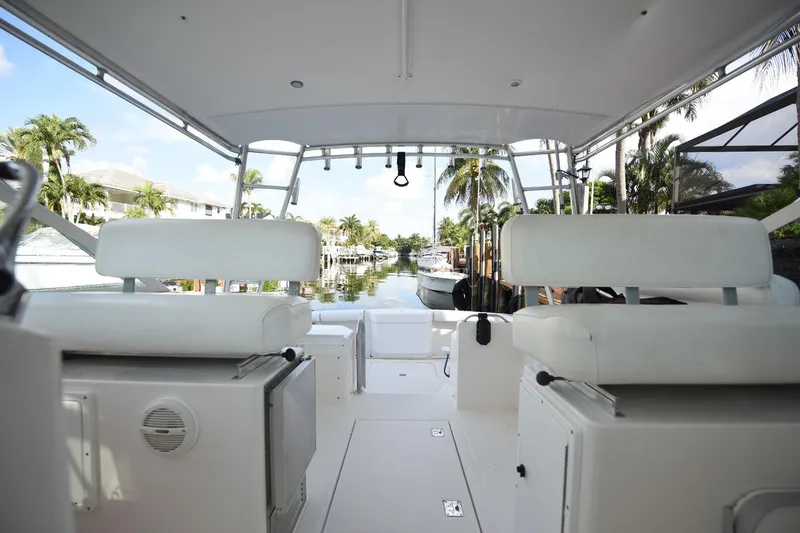 Slide: The Image of 2002 Cabo 35 Express boat interior with white seating, docked near palm trees. - 66