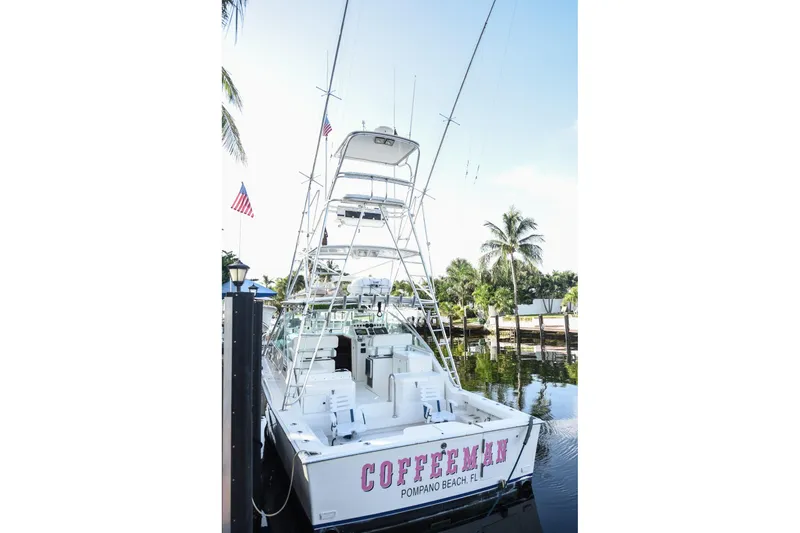 Slide: The Image of 2002 Cabo 35 Express boat docked, featuring fishing tower and palm trees in the background. - 34
