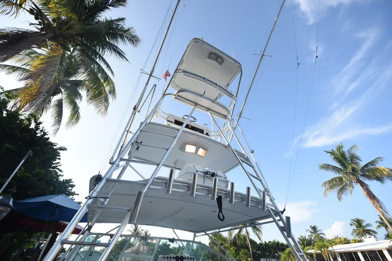 Slide: The Image of 2002 Cabo 35 Express boat with tower, surrounded by palm trees under a clear blue sky. - 12