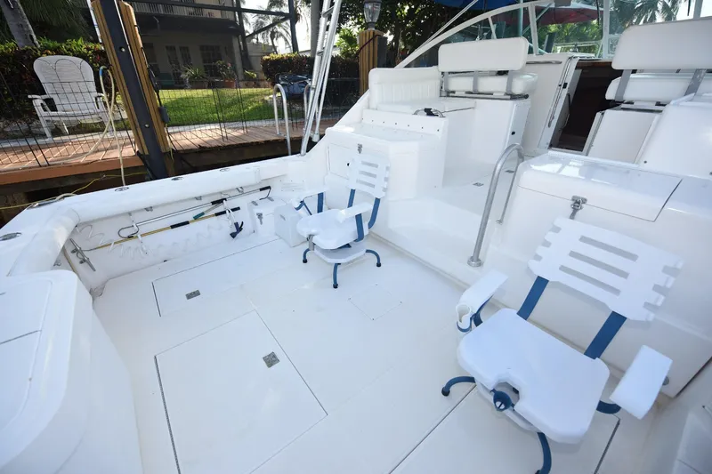 Slide: The Image of 2002 Cabo 35 Express boat deck with white seating and fishing rod holders. - 31