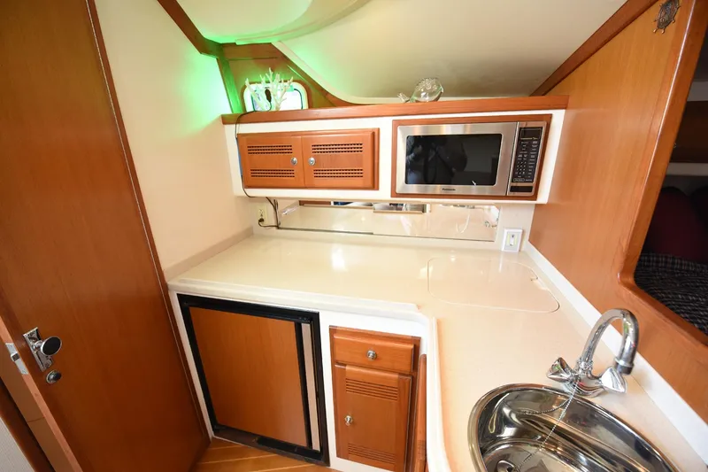 Slide: The Image of Compact kitchen area in a 2002 Cabo 35 Express boat with microwave and sink. - 83