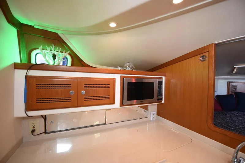 Slide: The Image of 2002 Cabo 35 Express interior with microwave, wooden cabinets, and modern lighting. - 89