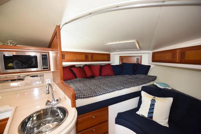 Slide: The Image of Interior of 2002 Cabo 35 Express yacht with cozy bed, kitchenette, and seating area. - 77