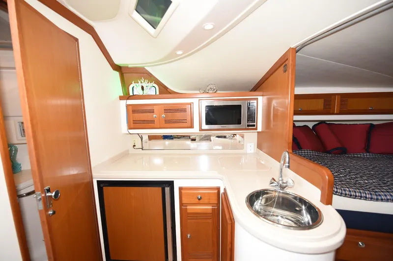 Slide: The Image of 2002 Cabo 35 Express yacht interior with kitchenette, featuring sink, microwave, and cozy sleeping area. - 84