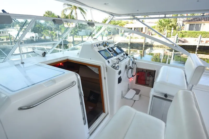 Slide: The Image of 2002 Cabo 35 Express boat cockpit with white seating and control panel, dockside view. - 42