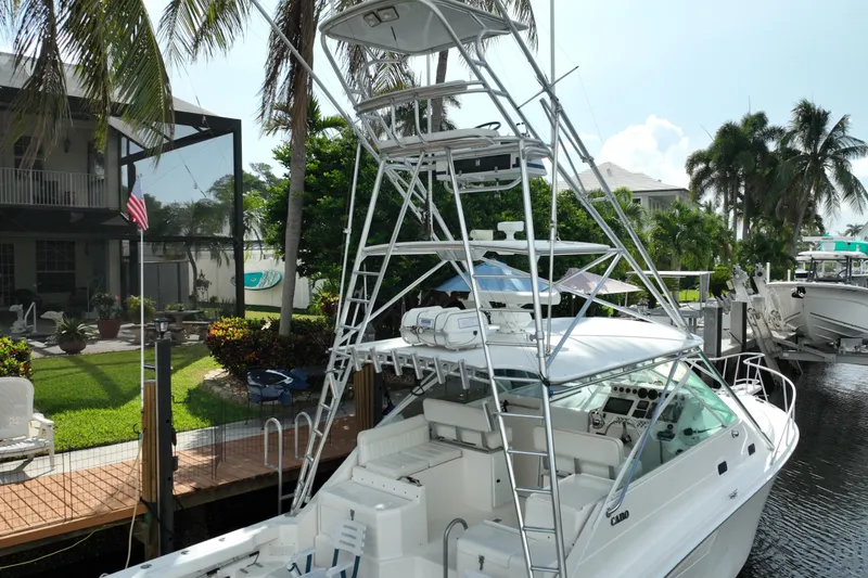 Slide: The Image of 2002 Cabo 35 Express boat docked near a lush, tropical backyard. - 4