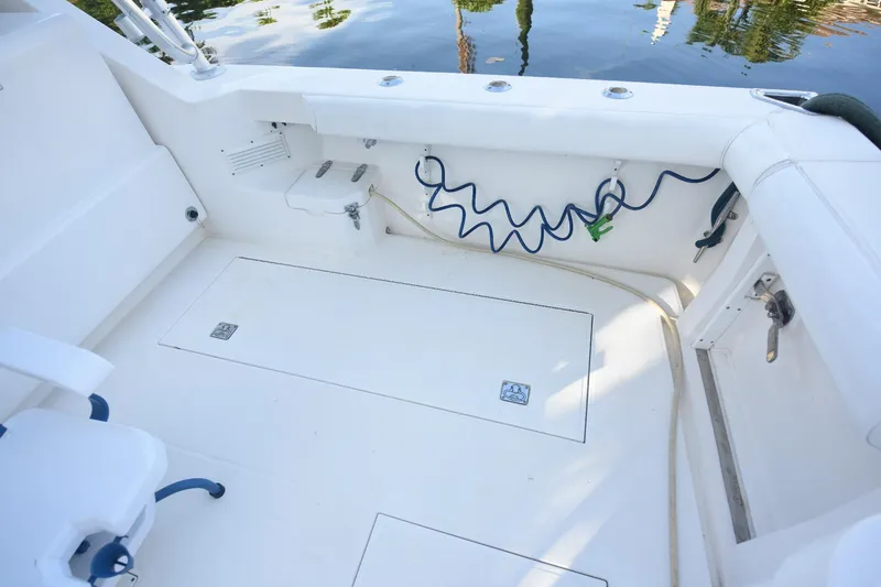 Slide: The Image of 2002 Cabo 35 Express boat deck with storage compartments and coiled hose. - 22