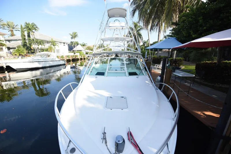 Slide: The Image of 2002 Cabo 35 Express boat docked by palm trees and waterfront homes. - 38