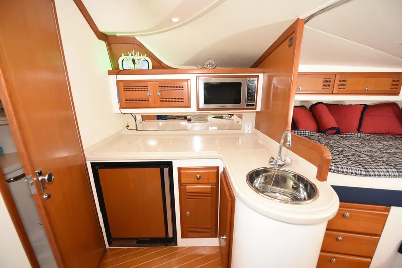Slide: The Image of 2002 Cabo 35 Express yacht interior with kitchenette, sink, microwave, and cozy sleeping area. - 85