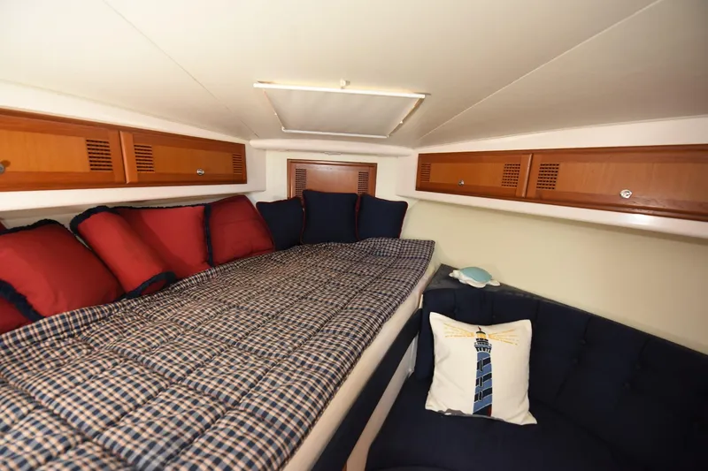 Slide: The Image of Cozy cabin interior of 2002 Cabo 35 Express with plaid bedding and wooden storage cabinets. - 76