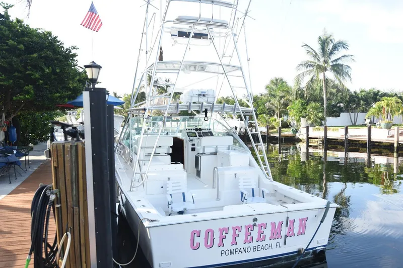 Slide: The Image of 2002 Cabo 35 Express boat docked, named "COFFEEMAN," in Pompano Beach, FL, with palm trees nearby. - 33