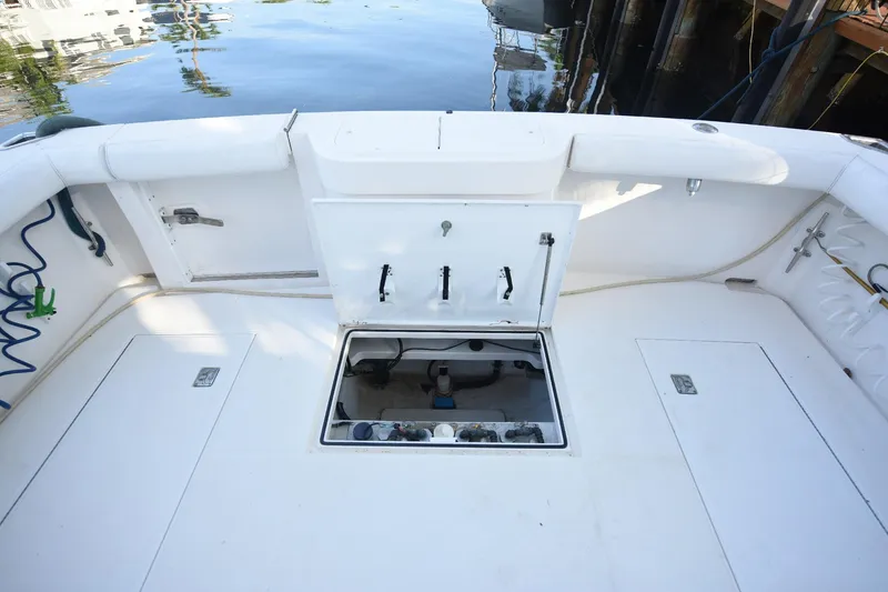 Slide: The Image of 2002 Cabo 35 Express boat deck with open hatch, docked by calm water. - 21