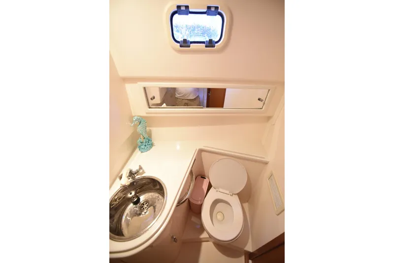 Slide: The Image of Compact bathroom in a 2002 Cabo 35 Express boat, featuring a sink and toilet. - 92