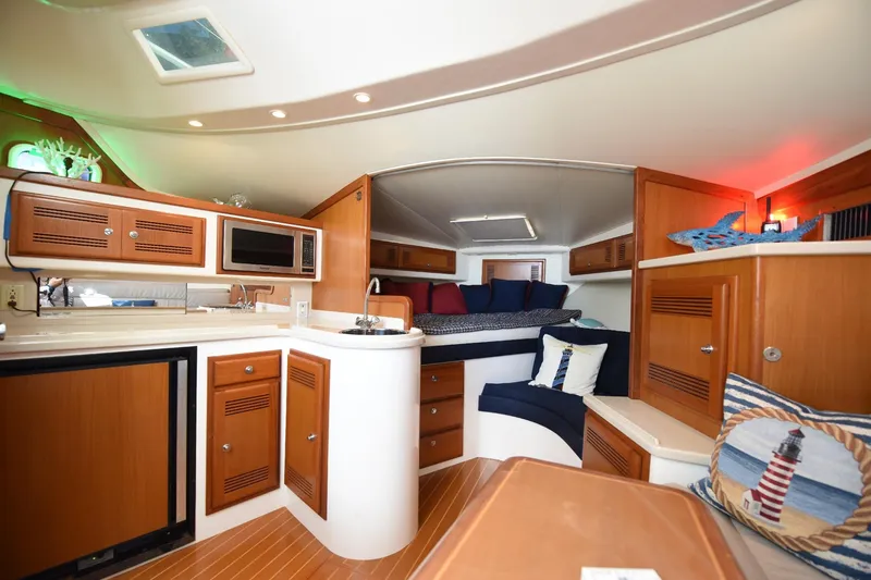 Slide: The Image of 2002 Cabo 35 Express yacht interior with cozy seating, kitchenette, and nautical decor. - 95