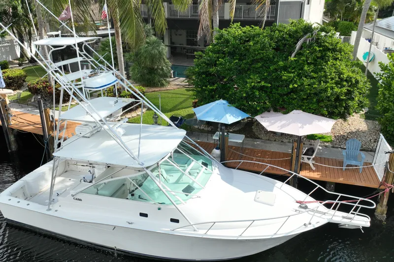 Slide: The Image of 2002 Cabo 35 Express boat docked near a lush garden and patio umbrellas. - 10