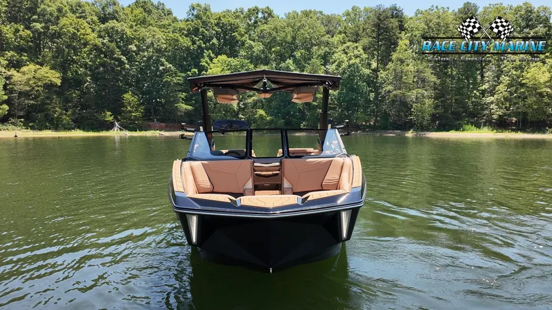 Slide: The Image of A modern Nautique G23 boat from 2027 on a calm lake, surrounded by lush forest. - 3