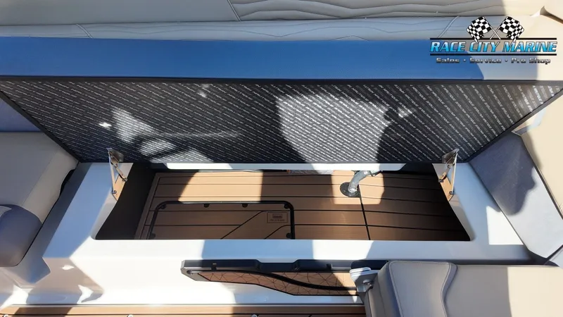Slide: The Image of The image shows a storage compartment on a 2027 Nautique G25 boat. The flooring is wooden. - 28