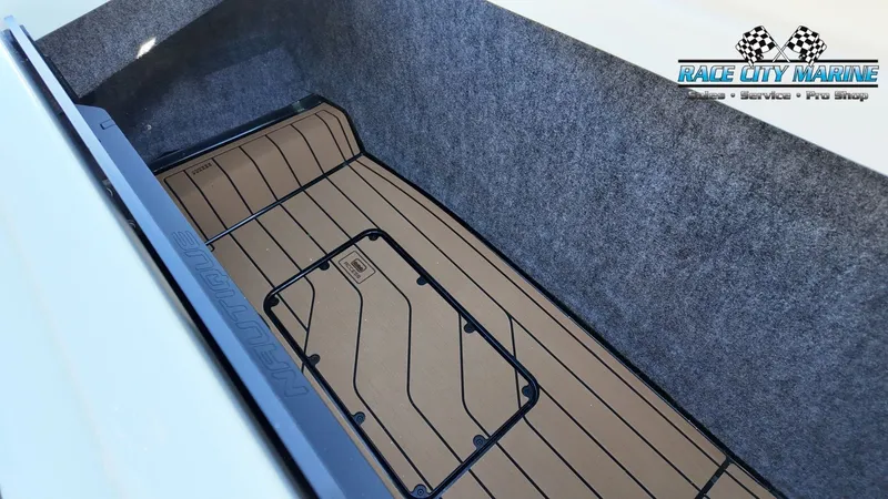 Slide: The Image of The 2027 Nautique G25 storage area is carpeted with a textured floor mat. - 30