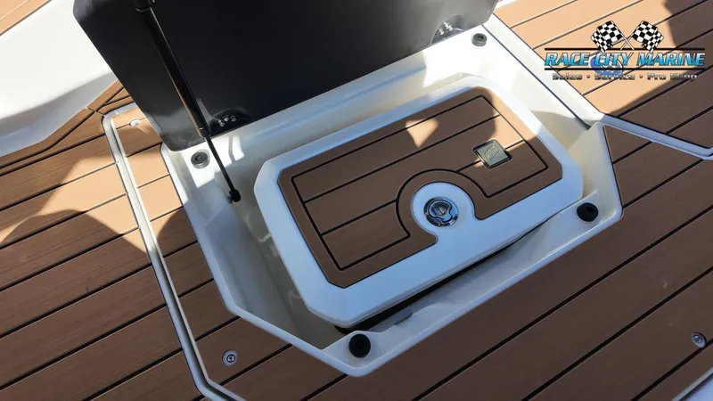 Slide: The Image of The image shows a storage compartment on a 2027 Nautique G25 boat with a wood finish. - 43